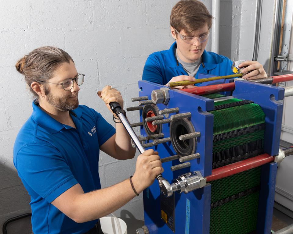 John Cadotte, left, and Jesse Buckley assemble a plate-and-frame heat exchanger as part of a New York State Energy Research and Development Authority project, which will be demonstrated in New York in 2025. Credit: Genevieve Martin/ORNL, U.S. Dept. of Energy