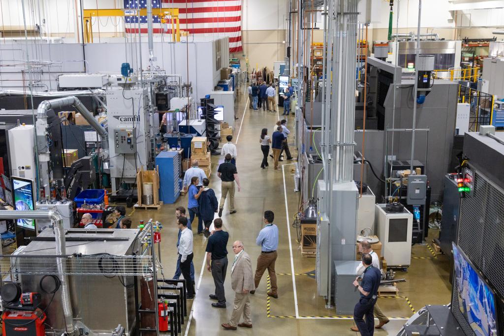 Arial shot of MDF building with machines and people scattered about, big american flag in the background