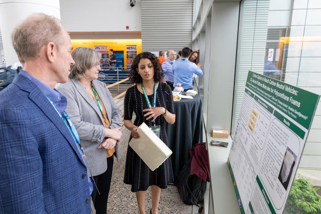 Two girls and a guy looking at a poster board.