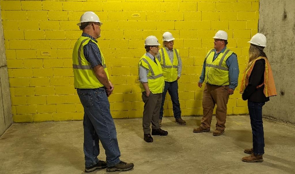 ORNL Director Stephen Streiffer, second from left, talks with members of the Proton Power Upgrade project next to the concrete block wall installed to provide radiation shielding during normal SNS operations. Credit: ORNL, U.S. Dept. of Energy