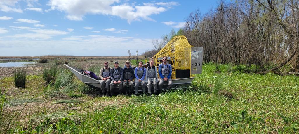 Team sits on airboat in the swamps of the Louisiana.