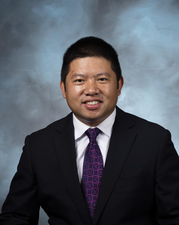 Man in black suit and tie smiles for a photo