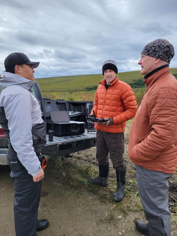 Daryl Yang standing outside at the bed of a truck with ORNL’s Geoff Schwaner and Misha Krassovski