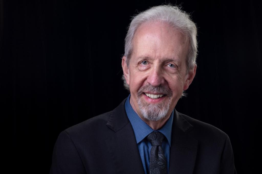 Larry Seiber poses for a photo with a black background
