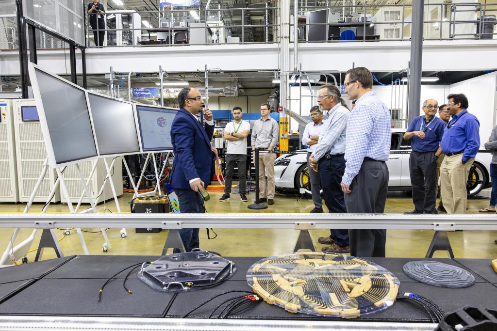 Group of 8 researchers gathered around the wireless charging presentation at the MDF