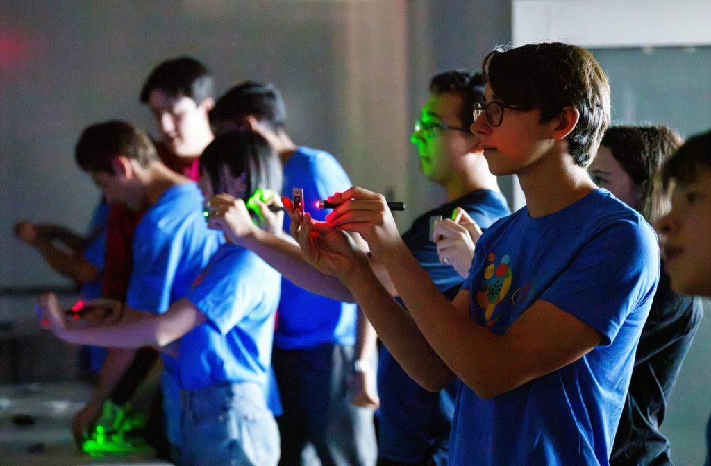 Students are holding up materials and shining red and green lights on them.