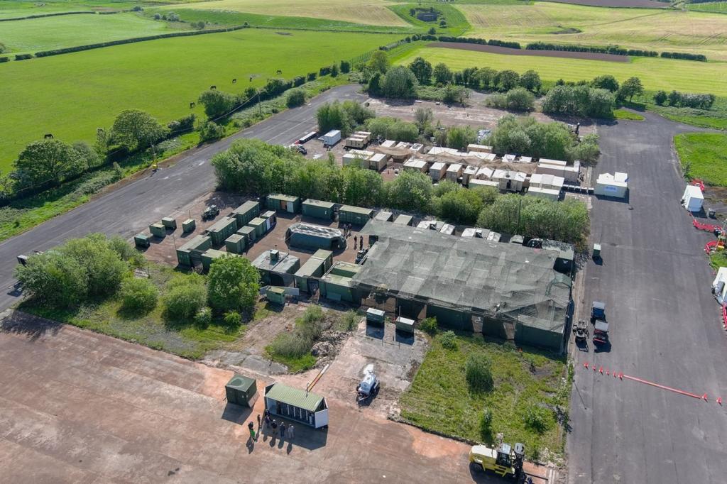 Arial view of MUF, with a little community of containers that are square shaped. There is green grass surrounding this small boxed in community