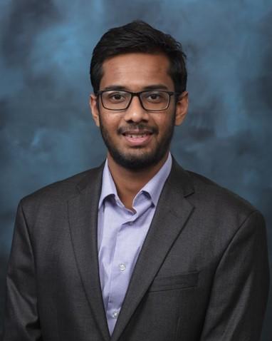 Photo of scientists Arka Daw in a suit with a blue and navy background