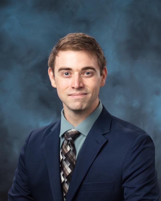 Richard Reed is posing for a photo in a blue jacket, nice tie and green shirt