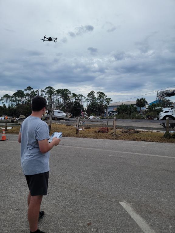 Man is flying drone in hurricane aftermath, holding the controller