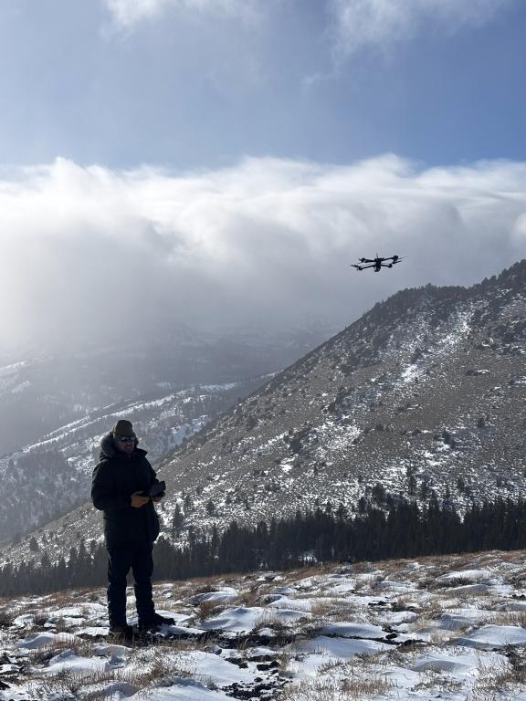 person flying a drone over a mountain