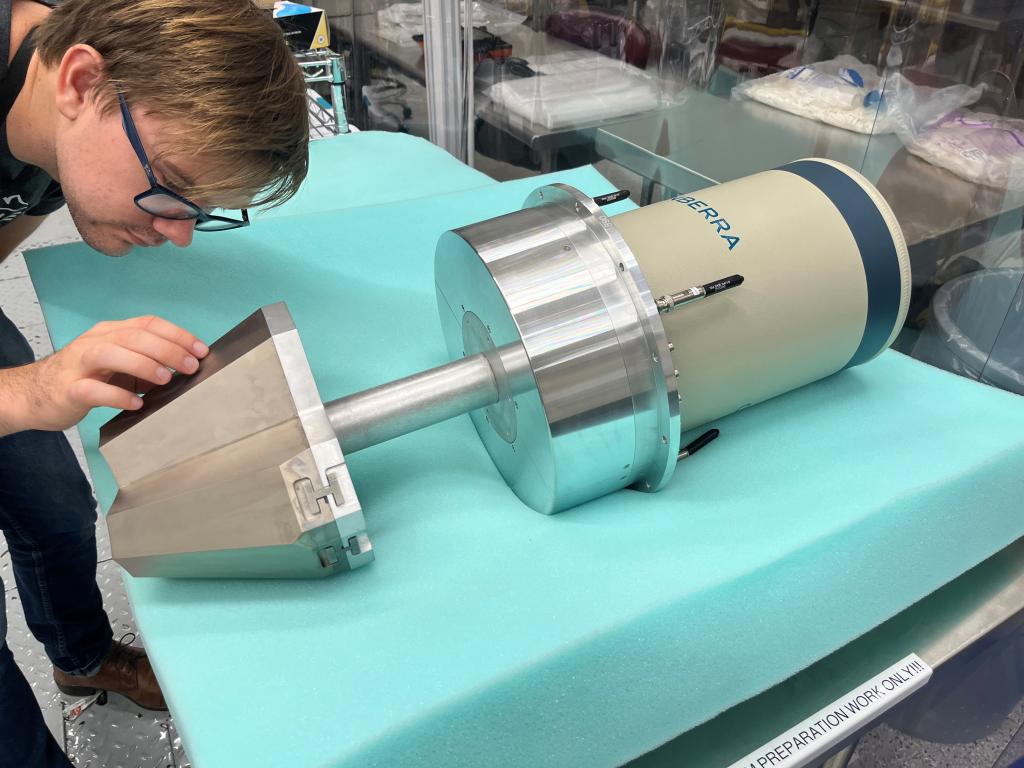 UT-ORNL’s Tim Gray closely inspects a germanium detector placed on foam padding in a lab, examining its metallic front end.