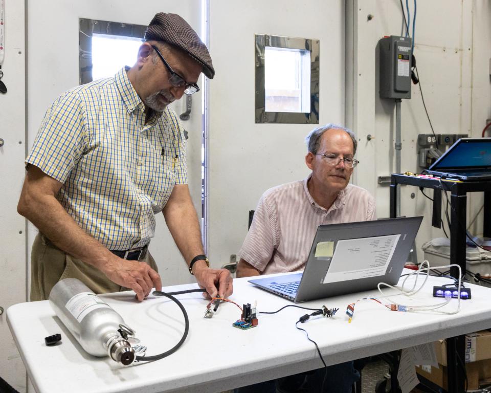 Researchers Moonis Ally and Stephen Killough demonstrate the refrigerant leak sensor they developed while evaluating the data output in 2022. Credit: Carlos Jones/ORNL, U.S. Dept. of Energy