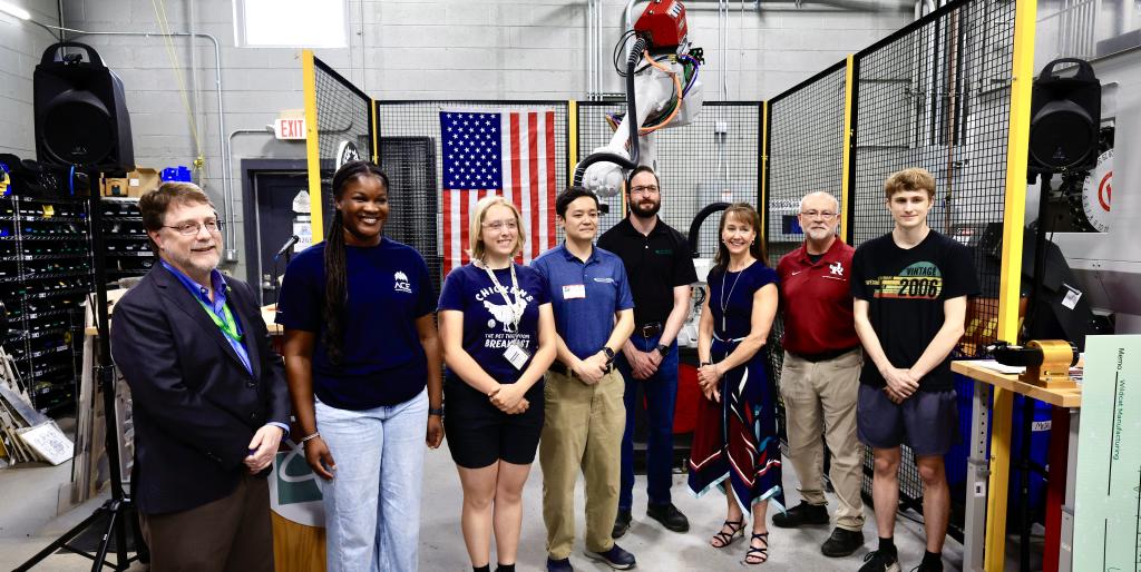 Leadership from ORNL and students from Oak Ridge High School pose for a photo in front of the 3D printing machine that UT-Battelle donated.