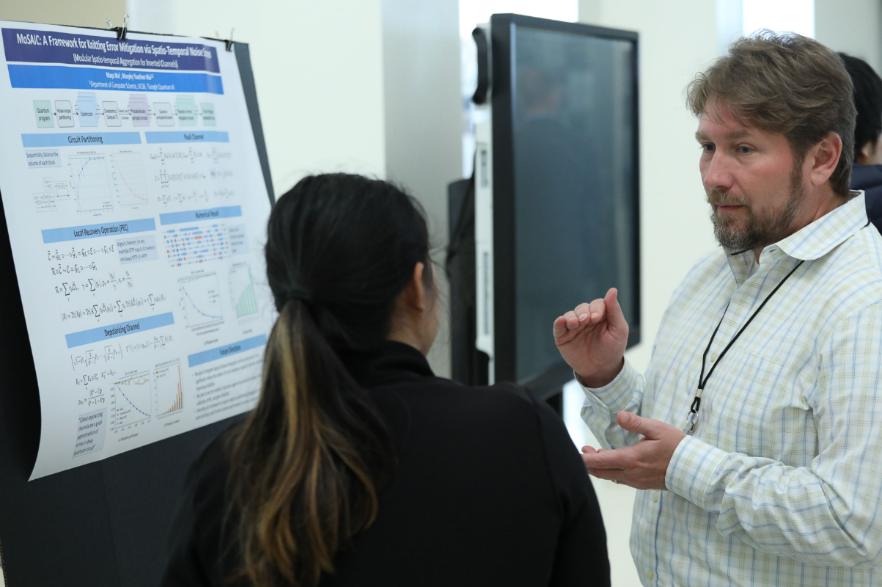 ORNL's Quantum Science Center Director is speaking to a attendee at Purdue University Quantum Science Center Summer School poster presentation