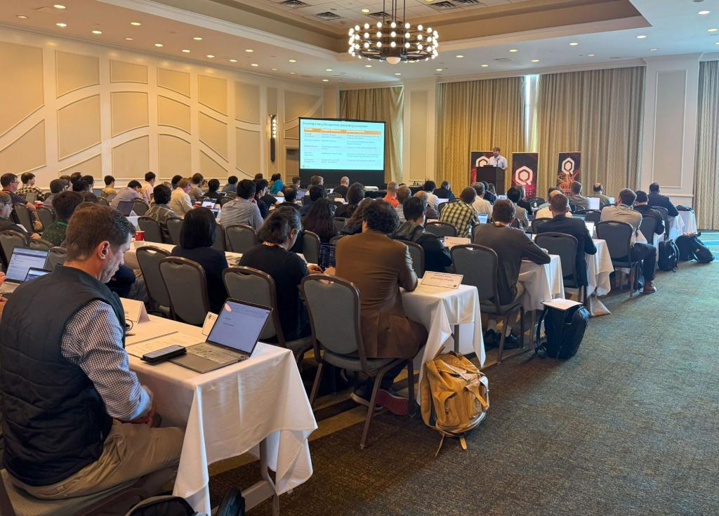Conference participants are sitting at cloth covered tables listening to lecture