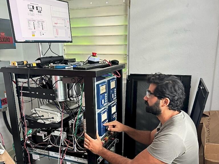 Engineer working with panels of electronics on a cart with a computer screen