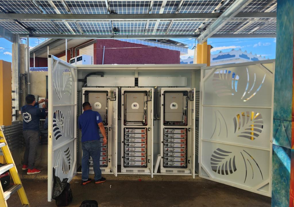 Image of men working on stacks of power electronics in a large metal cabinet
