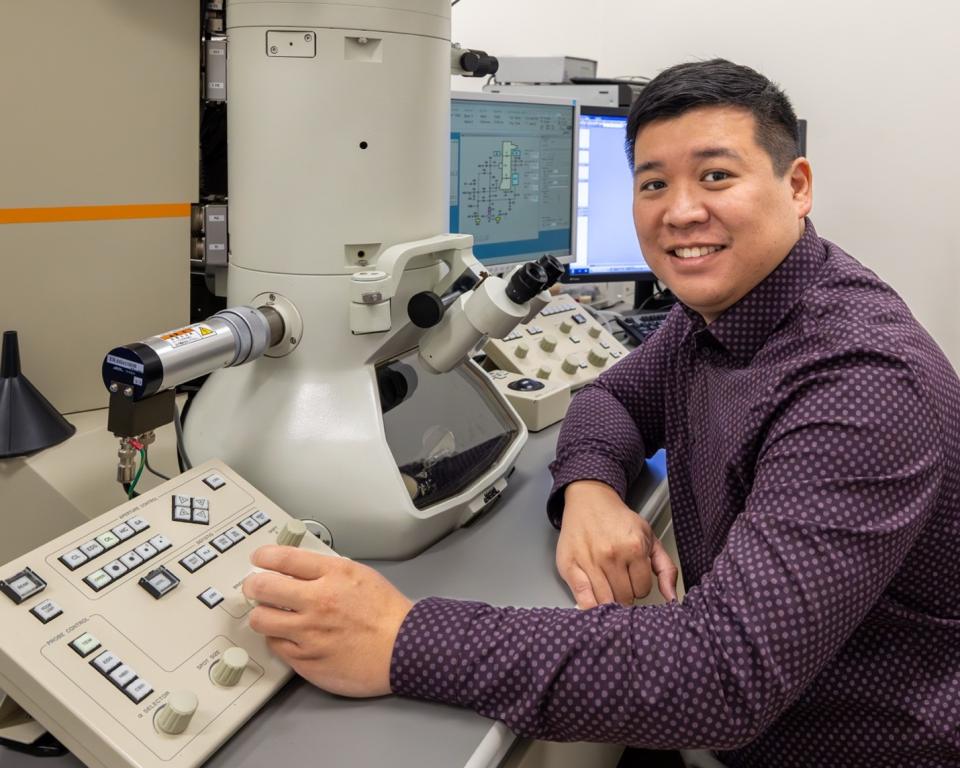 ORNL researcher is sitting at a transmission electron microscopy board in a lab at ORNL