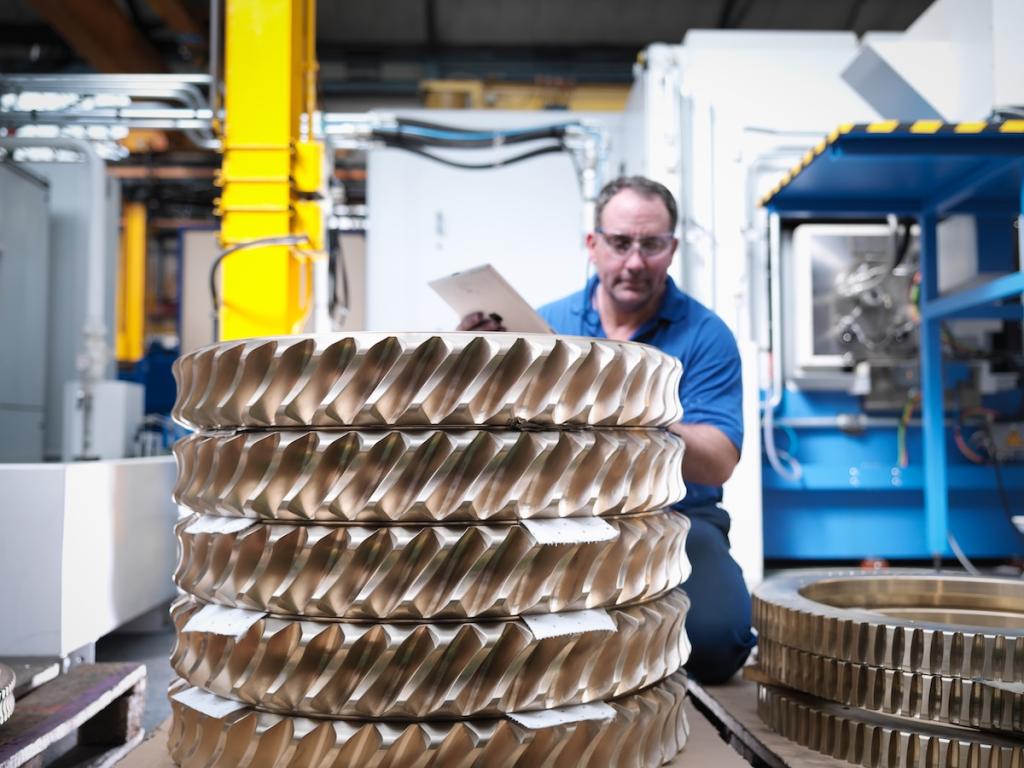 Engineer with bronze cogs in engineering factory. Image from Envato