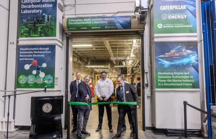 Three team members are standing cutting a green ribbon kicking off project with the installation of a 6-cylinder engine at the Department of Energy’s National Transportation Research Center at ORNL.