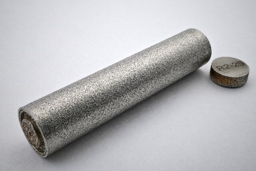 Singular stainless steel capsule laying flat with a close up of the cap that reads