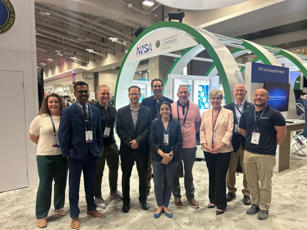 10 staff members are gathering inside the AI expo with a large green and white arch behind them