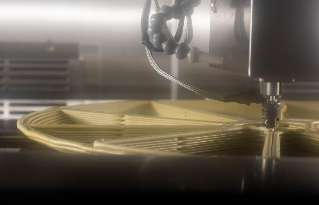 A view inside a JuggerBot 3D printer at the manufacturing demonstration facility. You can see the machine 3D printing material in a wheel format