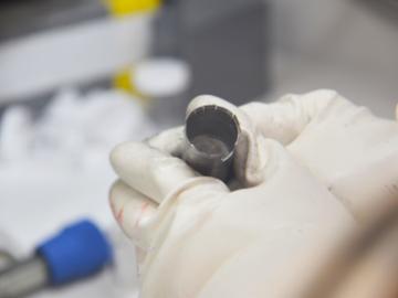 An ORNL researcher holds a capsule of molten salt. Preliminary experiments seem to indicate that irradiation can slow corrosion of metal in liquid salt. Credit: ORNL, U.S. Dept. of Energy