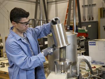 Oscar Martinez loads a special form capsule into the leak tester for a helium leak test in the packaging facility of the National Transportation Research Center. Credit: Jason Richards/ORNL, U.S. Dept. of Energy