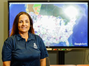 Isabelle Snyder standing in front of screen dislaying national map of US power grids