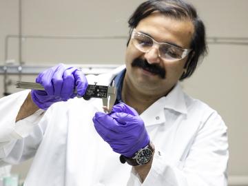 Samarthya Bhagia examines a sample of a thermoplastic composite material additively manufactured using poplar wood and polylactic acid. Credit: Carlos Jones/ORNL, U.S. Dept. of Energy