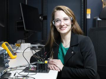 A woman sits at a desk with cybersecurity research equipment.