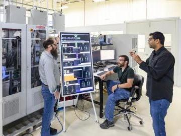 From left, Michael Starke, Steven Campbell and Madhu Chinthavali of ORNL discuss the configuration of the power electronics hub demonstrated with hardware in the low-voltage lab at GRID-C. Credit: Carlos Jones/ORNL, U.S. Dept. of Energy