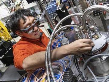 Yun-Yi Pai works with a closed-cycle dilution refrigerator designed for cryomagnetooptical microscopy at ORNL. Credit: Carlos Jones/ORNL, U.S. Dept. of Energy