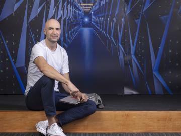 Aaron Ferber poses by a background of Summit, a supercomputer at Oak Ridge National Laboratory