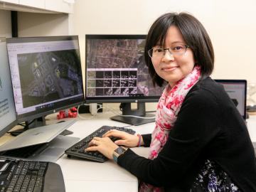 A woman works at her desk with multiple computer monitors.