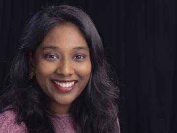 Portrait of Sreelekha Guggilam in purple shirt with black background.