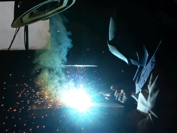 Welder with torch flare (Unsplash)