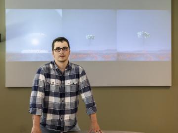 Cody Lloyd stands in front of images of historical nuclear field testing. The green and red dots are the machine learning algorithm recognizing features in the image. Credit: Carlos Jones/ORNL, U.S. Dept. of Energy