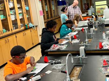 Group of young kids sitting at a lab table. 