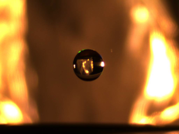 A small droplet of water is suspended in midair via an electrostatic levitator that lifts charged particles using an electric field that counteracts gravity. Credit: Iowa State University/ORNL, U.S. Dept. of Energy
