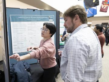 QSC Director Travis Humble, who gave a lunchtime talk on transitioning good ideas to device development, learns about one of the many quantum research efforts featured at the poster session. Credit: Alonda Hines/ORNL, U.S. Dept. of Energy 