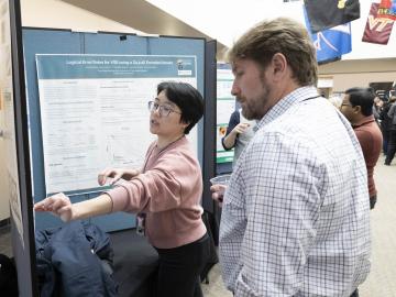 QSC Director Travis Humble, who gave a lunchtime talk on transitioning good ideas to device development, learns about one of the many quantum research efforts featured at the poster session. Credit: Alonda Hines/ORNL, U.S. Dept. of Energy