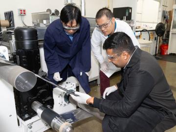 ORNL scientist Zhijia Du, white coat, former ORNL scientist Jianlin Li, blue coat, and Ateios CEO Rajan Kumar inspect battery components during a pilot production run. Credit: Kurt Weiss/ORNL, U.S. Dept of Energy