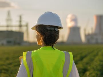 Stock image of woman in hazard vest with reactor stack in background