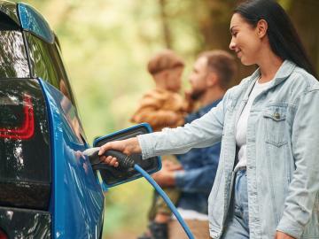 Woman charging electric vehicle