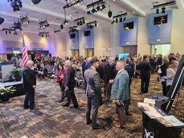 People in a large convention room networking before a presentation