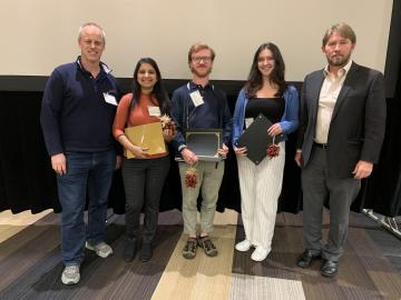 5 people (boy, girl, boy, girl, boy) are standing holding an award. 