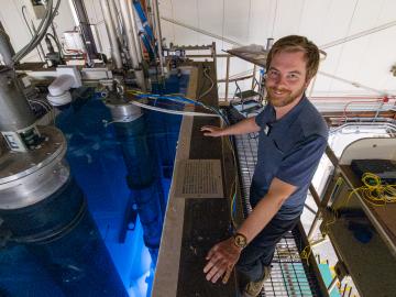 Man in a blue polo is standing over blue water 